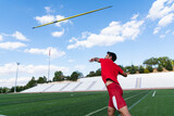 Fototapeta Zachód słońca - An athletic man throws the javelin in the stadium.