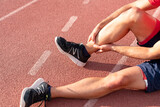 Fototapeta Zachód słońca - Athlete with injured ankle is holding his knee. knee and foot joint injuries