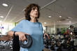 © Raul Navarro/Stocksy - Senior woman exercising with weights at gym