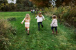 © Serena Burroughs/Stocksy - happy kids running together toward family outdoors in autumn