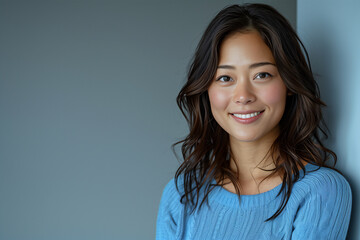 Portrait of a smiling woman in a blue sweater against a blue background.