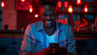 © Nataliia_Trushchenko - A man is sitting on a couch and smiling while looking at his cell phone. Concept of relaxation as the man is engaged in his phone. African man smiling while using phones tablet at home at night