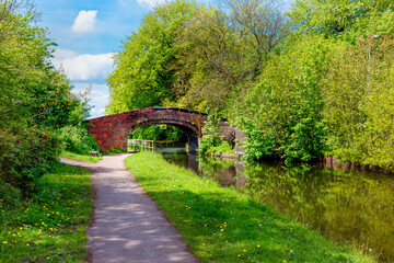 historic brick bridge over serene canal with lush trees on a bright spring day