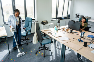 A woman vacuums in the office after a celebration
