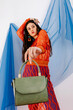 © Tania Cervian/Stocksy - Supermodel with long hair showing crocodile skin bag and looking away