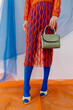 © Tania Cervian/Stocksy - Faceless model in fishnet outfit and pantyhose standing with handbag