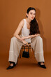 © Tania Cervian/Stocksy - Stylish female sitting on chair with handbag and in studio