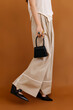 © Tania Cervian/Stocksy - Crop female model in stylish outfit standing behind brown background