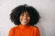 © VICTOR TORRES/Stocksy - Joyful woman with curly hair in an orange sweater