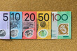 © Shava Cueva/Stocksy - Australian money of different denominations arranged in a row