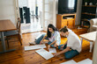 © Pedro Merino/Stocksy - Women working together to assemble furniture at home