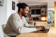 © Jovo Jovanovic/Stocksy - Smiling male freelancer using laptop at home