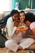 © BONNINSTUDIO/Stocksy - Happy girlfriends with burning candles on cake on birthday party