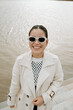 © Azamat Mukanov/Stocksy - Asian woman in sunglasses by the boardwalk.