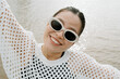 © Azamat Mukanov/Stocksy - Asian woman in sunglasses by the boardwalk.