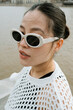 © Azamat Mukanov/Stocksy - Asian woman in sunglasses by the boardwalk.