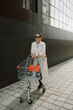 © Azamat Mukanov/Stocksy - Asian woman in sunglasses with a shopping cart in the city