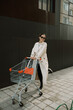 © Azamat Mukanov/Stocksy - Asian woman in sunglasses with a shopping cart in the city