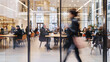 © bensaid - A blurred photo captures an office space with glass walls, showing busy people working at desks and walking around in the background.