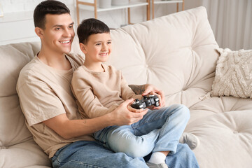 Canvas Print - Happy father with his little son playing video game on sofa at home