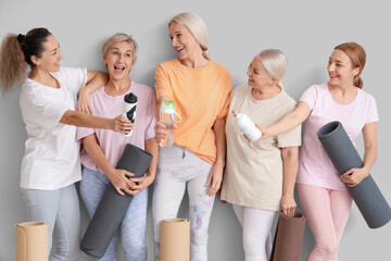 Wall Mural - Group of mature women with yoga mats and water bottles on light background