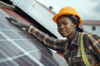 © m.malinika - Female worker with protective jacket and helmet is attaching solar panels to the roof of the factory. Solar panels generation, sustainability eco-friendly concept.