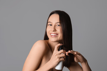 Poster - Young woman with cosmetics for hair treatment on grey background