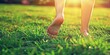 © piai - Barefoot woman's feet walking on garden green grass in the park. Sunlight and nature background