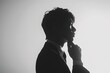 © YONG - A black and white silhouette of an Asian man, gazing at his hand and touching his chin with some small gestures