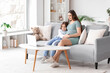 © Pixel-Shot - Little girl with her pregnant mother on sofa watching cartoons at home