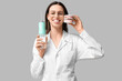 © Pixel-Shot - Female dentist with oral irrigator and jaw model on grey background