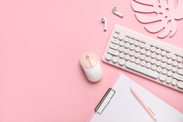 PC keyboard, mouse, earphones and stationery on pink background