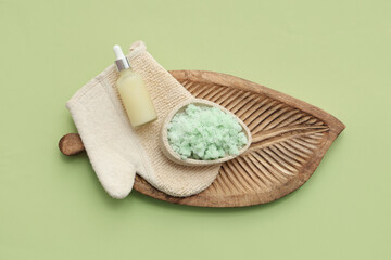 Wall Mural - Wooden plate with natural body scrub, massage glove and essential oil on green background