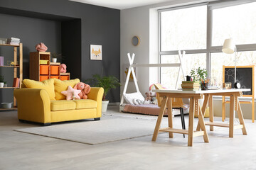 Sticker - Interior of stylish childrens room with workplace, toys and yellow sofa