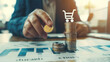 © Michael - Hand placing a coin on a stack with a shopping cart icon, symbolizing inflation