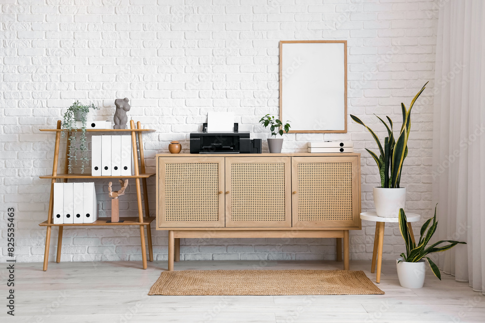 Interior of light office with printer on commode, plants and shelf unit