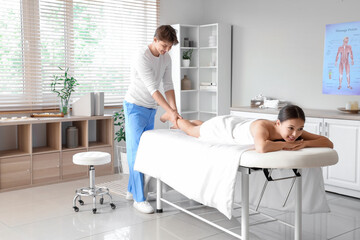 Canvas Print - Male therapist massaging young woman's leg in spa salon