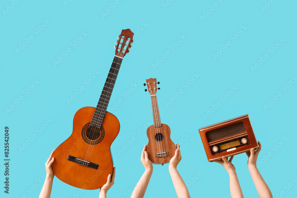 Women with guitars and radio receiver on blue background