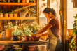 © VisualProduction - Hispanic woman potting plants in her garden shed with sunset light filtering in.