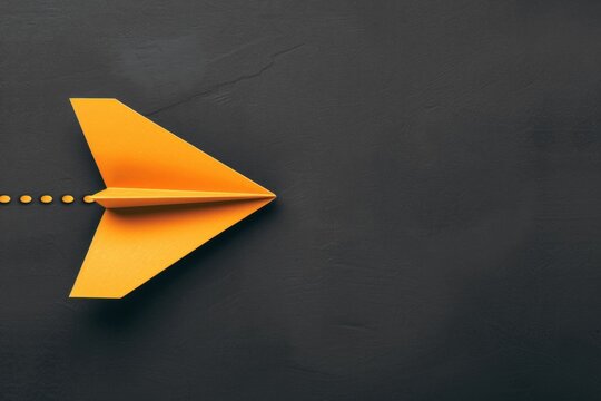 Yellow origami plane against a black background with copy space - business innovation, leadership skills, visionary thinking