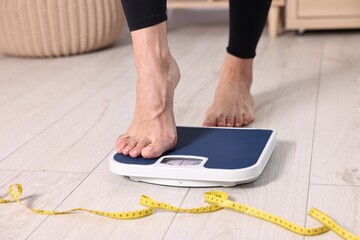 Poster - Woman stepping on floor scale and measuring tape at home, closeup. Weight control