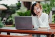 © Satori Studio - A woman is sitting at a table with a laptop and books. She is smiling and she is enjoying her time