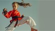 © CNISAK - a young girl in mid-air performing a high kick, wearing a red and white martial arts uniform with a black belt, indicating her advanced skill level