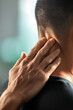 © GreenMOM - Close-up of person touching their neck, illustrating pain or discomfort. Focus on hand and neck in soothing environment.