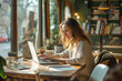 © Thodsapol - Smiling woman working on laptop in a cafe
