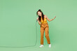 © ViDi Studio - Full body young woman of African American ethnicity wearing yellow tank shirt top sing song in microphone at karaoke club isolated on plain pastel green background studio portrait. Lifestyle concept.