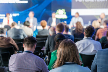 Wall Mural - Diverse group of business professionals attending a conference, focusing on a panel discussion. The image captures the audience from behind, emphasizing active listening and engagement.