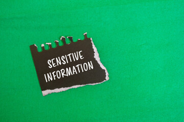 Sensitive information words written on ripped black paper piece with green background. Conceptual sensitive information symbol.