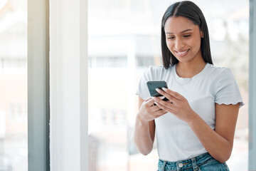 Fototapete - Reading, woman and smartphone by window in office for social media, communication or marketing for company. Creative businessperson, happy and text in workplace for networking, technology or contact