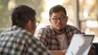 © VK Studio - Two colleagues engaged in a focused business conversation over a laptop in a casual setting.
